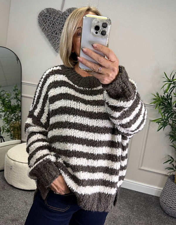 Lady wearing a striped Jumper taking a mirror selfie in a room with plants and decor.